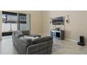 Modern living room with tile flooring, gray sectional couch, and sliding door to lanai at 12189 Beach Fern Rd, Orlando, FL 32824