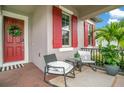 Cozy front porch with seating, potted plants, and red shutters accenting the front windows at 13227 Spring Grove Way, Winter Garden, FL 34787