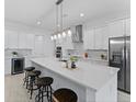 Modern kitchen with stainless steel appliances, a large center island, and sleek white cabinetry at 200 Snowy Orchid Way, Lake Alfred, FL 33850