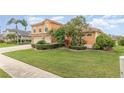Landscaped front yard with lush green grass, manicured shrubs, and tropical plants at 2326 Wintermere Pointe Dr, Winter Garden, FL 34787