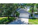 View of the home's exterior showing the garage, well-maintained lawn, and mature trees providing shade at 418 S Summerlin Ave, Sanford, FL 32771
