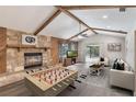 Inviting living room featuring a stone fireplace, wood beams, foosball table, and sliding glass doors to the outdoors at 655 E Lake View Rd, Lake Alfred, FL 33850