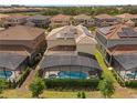 Aerial view of pool with screen enclosure and solar panels on roof of this home at 7630 Oakmoss Loop, Davenport, FL 33837