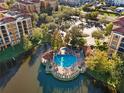 An aerial view of a community pool on a small island in a lagoon, surrounded by lush trees and beautiful buildings at 12521 Floridays Resort Dr # 307F, Orlando, FL 32821