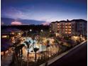 A view of a lagoon style pool surrounded by palm trees with the buildings lit up at dusk at 12521 Floridays Resort Dr # 307F, Orlando, FL 32821