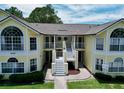 Inviting yellow condo building with white trim, staircases to balconies, and well-manicured landscaping at 2040 Royal Bay Blvd # 30, Kissimmee, FL 34746