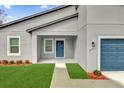 Welcoming front entrance with a well-maintained lawn leading to a blue front door at 2415 Sw 165Th Pl, Ocala, FL 34473
