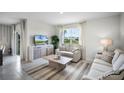 Bright living room with neutral sofas, a patterned rug, and a window with backyard views at 2610 Grandbury Grove Rd, Lakeland, FL 33811