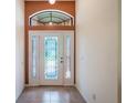 Bright foyer featuring a decorative front door, transom window, and neutral tile flooring at 27307 Pine Straw Rd, Leesburg, FL 34748