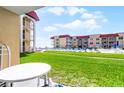 Condo lawn area featuring a swimming pool, building, outdoor seating, and well-manicured green grass at 3801 S Atlantic Ave # 105, New Smyrna Beach, FL 32169