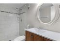 Bathroom features a tiled shower and a sink with a round mirror in this compact space at 3801 S Atlantic Ave # 105, New Smyrna Beach, FL 32169