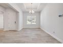 Open living room has neutral walls, tray ceiling, modern chandelier and beautiful tile flooring at 388 Nowell Loop, Deland, FL 32724