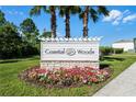 Coastal Woods community sign with flower bed and palm trees, welcoming residents and visitors alike at 512 Stowers Dr, New Smyrna Beach, FL 32168