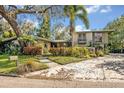 Two-story home featuring mature trees, colorful plants, and inviting walkway leading to the main entrance at 605 Sweetbriar Rd, Orlando, FL 32806