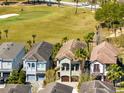 Aerial view of neighborhood homes, showcasing a house near a green golf course and lush landscaping at 1004 Castle Pines Ct, Reunion, FL 34747