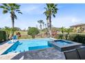 Relaxing backyard features a refreshing pool, hot tub, lush palm trees, and scenic golf course views at 1004 Castle Pines Ct, Reunion, FL 34747