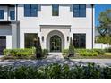 Elegant home entrance featuring a striking arched doorway, meticulous landscaping, and stone walkway at 1833 Loch Berry Rd, Winter Park, FL 32789