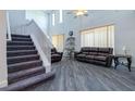 Living room with a staircase, high ceilings, grey wood-look floors, and many windows at 1905 Snapper Dr, Kissimmee, FL 34759