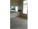 Carpeted living room showing a serving hatch to a kitchen and window at 860 N Orange Ave # 444, Orlando, FL 32801