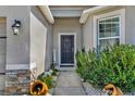 Inviting front entrance with a stylish black door, decorative plants, and stone accents at 3086 Brenton Manor Loop, Winter Haven, FL 33881
