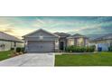 Inviting single-Gathering home with a well-maintained lawn, attached garage, and stylish exterior lighting at 3086 Brenton Manor Loop, Winter Haven, FL 33881