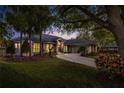 Beautiful single-story home featuring a well-manicured lawn, mature trees, and a circular driveway leading to a 3-car garage at dusk at 5337 Foxshire Ct, Orlando, FL 32819