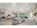 Elegant living room with a tray ceiling, featuring hardwood floors, neutral furniture, and access to an outdoor patio at 8400 Bridgeport Bay Cir, Mount Dora, FL 32757