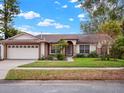 Charming single-story home with a well-manicured lawn, mature trees, and an attached two-car garage at 14540 Pointe East Trl, Clermont, FL 34711