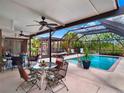 Relaxing covered lanai with a ceiling fan, outdoor dining set, and a view of the screened pool at 14540 Pointe East Trl, Clermont, FL 34711