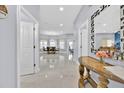 Open entryway with gleaming tile floors leading to the dining room with a chandelier and abundant natural light at 210 Vista Loop, Davenport, FL 33897
