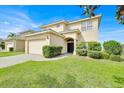 Well-manicured lawn and shrubbery compliment the two-story home featuring an attached two-car garage at 210 Vista Loop, Davenport, FL 33897