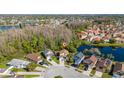 A picturesque aerial view showcasing a home nestled near a serene lake and surrounded by verdant trees in a vibrant community at 2405 Cancun Ct, Kissimmee, FL 34743