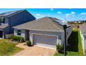 Charming single Gathering home featuring a brick walkway, well-maintained lawn, and a two-car garage at 249 Hamlet Loop, Davenport, FL 33837