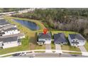 Stunning aerial view of a two-story home with solar panels nestled near a pond and other community houses at 2984 Sanctuary Dr, Clermont, FL 34714