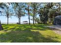 Expansive green backyard featuring a gazebo, mature trees, and a well-manicured lawn overlooking the serene water at 35624 Cypress Ct, Leesburg, FL 34788