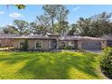 Charming single-story home features arched windows, a well-manicured lawn, and lush landscaping at 35624 Cypress Ct, Leesburg, FL 34788