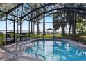 A screened-in pool area with a sparkling pool, offering views of the picturesque backyard and waterfront gazebo at 35624 Cypress Ct, Leesburg, FL 34788