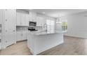 Open kitchen featuring an island with quartz countertops, stainless steel appliances, modern fixtures, and white cabinetry at 4198 Barbuda Ln, Kissimmee, FL 34758