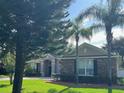 Inviting single-story home showcasing stone accents, lush greenery, and a meticulously manicured lawn at 4847 Lake Milly Dr, Orlando, FL 32839