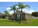Charming single-story home featuring stone accents, well-manicured lawn and mature palm trees on a sunny day at 4847 Lake Milly Dr, Orlando, FL 32839