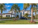 Elegant white home with arched windows, a tile roof, and a beautifully manicured lawn with a black luxury car at 13305 Bellaria Cir, Windermere, FL 34786