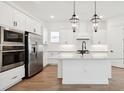 Bright kitchen with white cabinetry, stainless steel appliances, a central island, and modern pendant lighting at 15543 Gentle Rain Dr # 197, Winter Garden, FL 34787