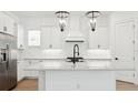 Modern kitchen featuring white cabinets, stainless steel appliances, a large island, and designer light fixtures at 15543 Gentle Rain Dr # 197, Winter Garden, FL 34787