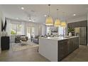 Open-concept kitchen and living room with modern lighting, stainless steel appliances, and a cozy seating area at 15567 Gentle Rain Dr # 194, Winter Garden, FL 34787