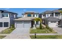 Daytime view of a modern two-story home with a well-kept lawn, stone accents, and a two-car garage at 15847 Vetta Dr, Bella Collina, FL 34756