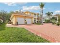 View of the home's three-car garage with a red brick driveway and manicured landscaping at 2747 Kissimmee Bay Cir, Kissimmee, FL 34744