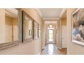 Bright hallway features tile floors, crown molding, multiple mirrors, and a front door letting in natural light at 3965 Kennebunk Loop, Mount Dora, FL 32757