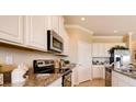 Beautiful kitchen features stainless steel appliances, granite countertops, and modern white cabinetry at 3965 Kennebunk Loop, Mount Dora, FL 32757