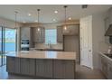 Modern kitchen featuring gray cabinets, a center island with quartz countertop and stainless steel appliances at 4203 Barbuda Ln, Kissimmee, FL 34758