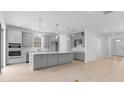 Modern kitchen with gray cabinets, stainless steel appliances, a large island and wood-look floors at 4203 Barbuda Ln, Kissimmee, FL 34758
